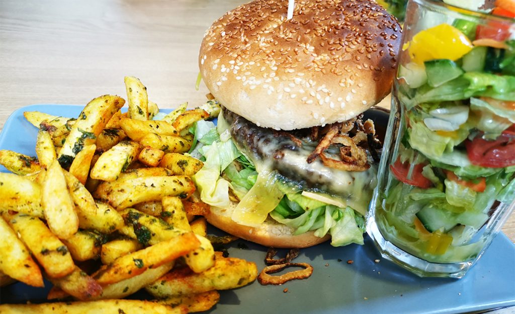 Foto von einem Burger mit Pommes in dem Biergarten der Kollegen.